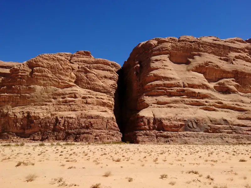 Eine schmale Felsschlucht, die zwei große Felswände in der Wüste trennt.