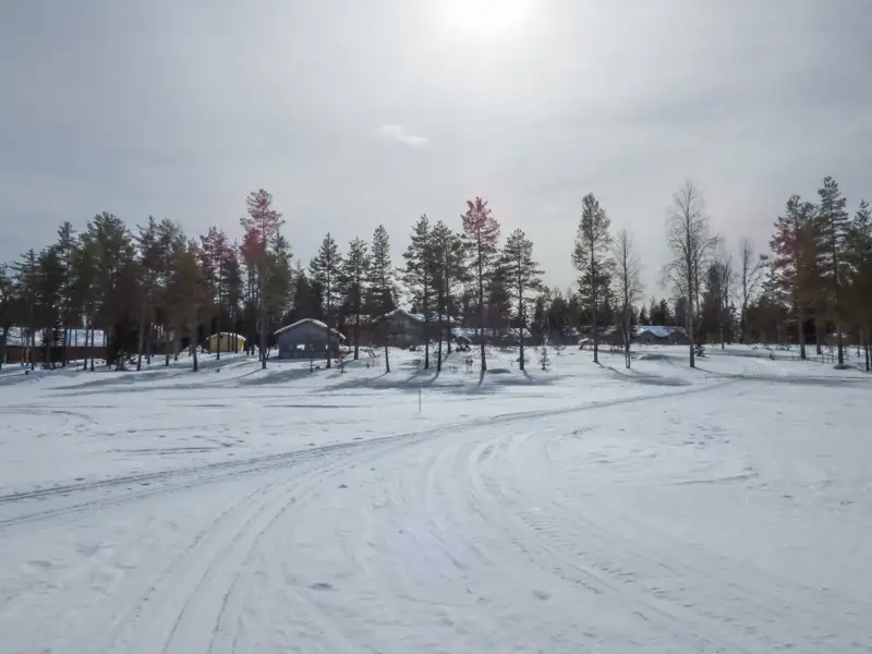 Winterlandschaft mit Schnee, Häusern und Bäumen.