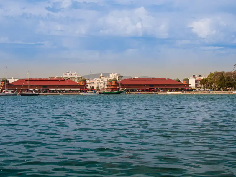 Hafenansicht mit Markthalle und Booten.