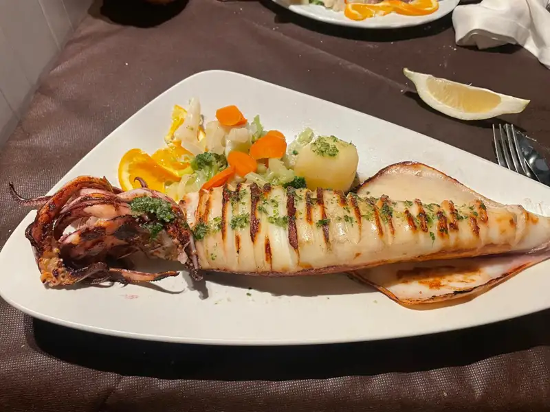 Gegrillter Tintenfisch serviert mit Gemüse.