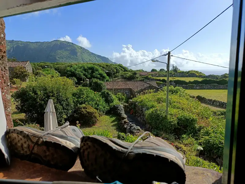 Blick aus dem Fenster auf die Landschaft mit Wanderschuhen, bereit für die nächste Wanderung.