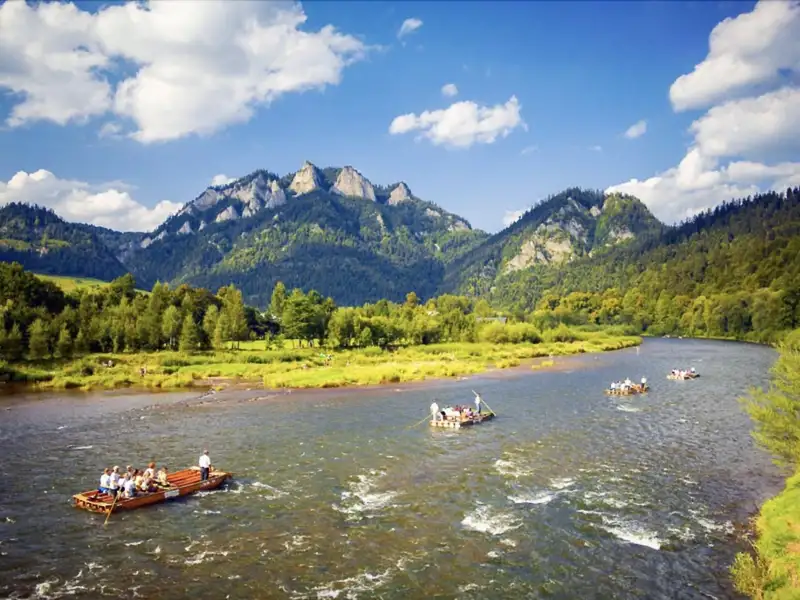 Flöße auf einem Fluss mit Bergen im Hintergrund.