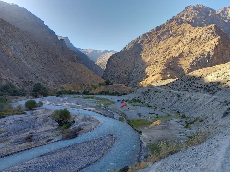 Flusslandschaft und Zeltplatz in einem Gebirgstal.