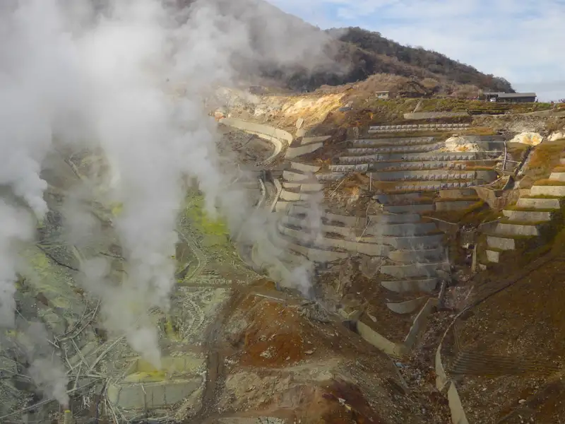 Vulkanische Aktivität mit Dampf und terrassierten Hängen.