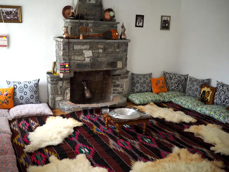 Traditioneller Wohnraum mit Kamin und Sitzgelegenheiten.