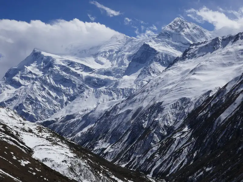 Schneebedeckte Berge im Hintergrund und ein verschneites Tal im Vordergrund.