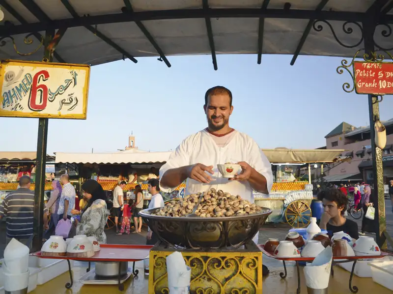 Straßenhändler mit einer Schüssel voller Schnecken auf dem Djemaa el Fna, Marrakesch.