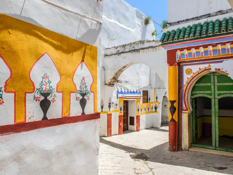 Traditionelle Architektur und Wandmalereien in einer Gasse.