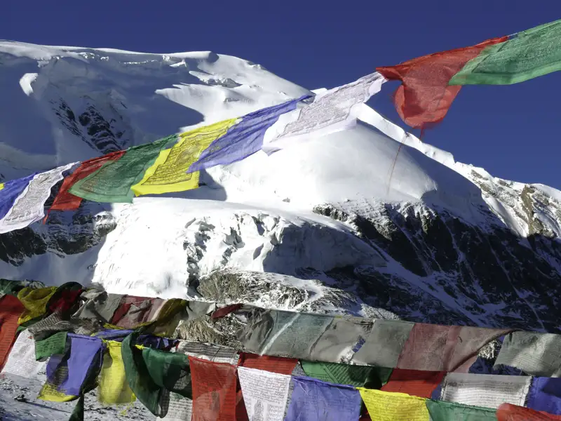 Gebetsfahnen vor schneebedecktem Bergpanorama