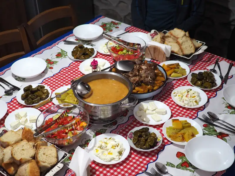 Tisch mit verschiedenen lokalen Gerichten, wie Suppe, Fleisch, gefüllte Weinblätter und Salat, die während der Reise genossen wurden.
