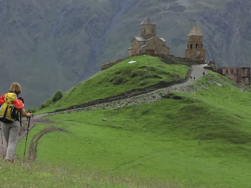 Wanderer auf dem Weg zu einer historischen Kirche in den Bergen.
