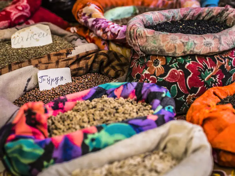 Verschiedene Gewürze in bunten, gemusterten Säcken auf einem Markt.