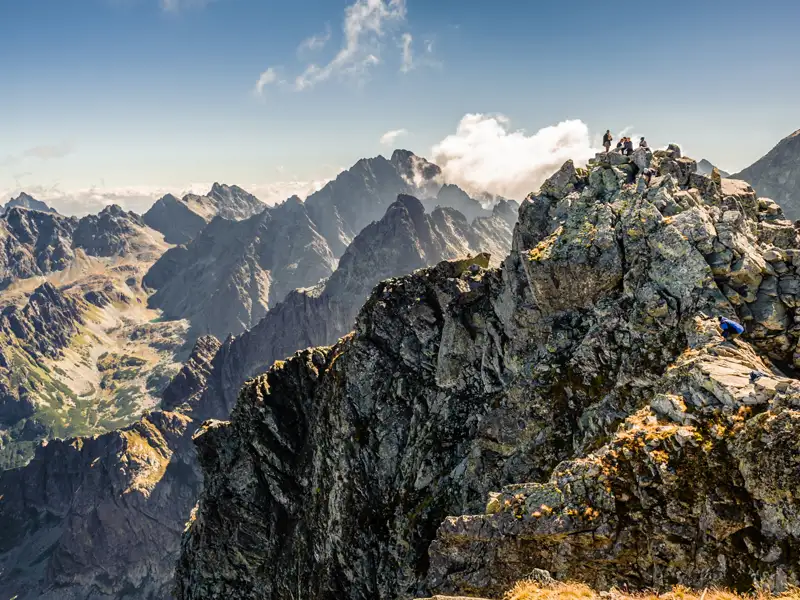Wanderer auf einem felsigen Gipfel in der Hohen Tatra mit Blick auf das umliegende Gebirge.