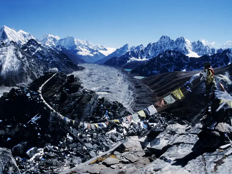 Gebetsfahnen wehen im Wind an einem Aussichtspunkt über einem Gletscher im Himalaya.