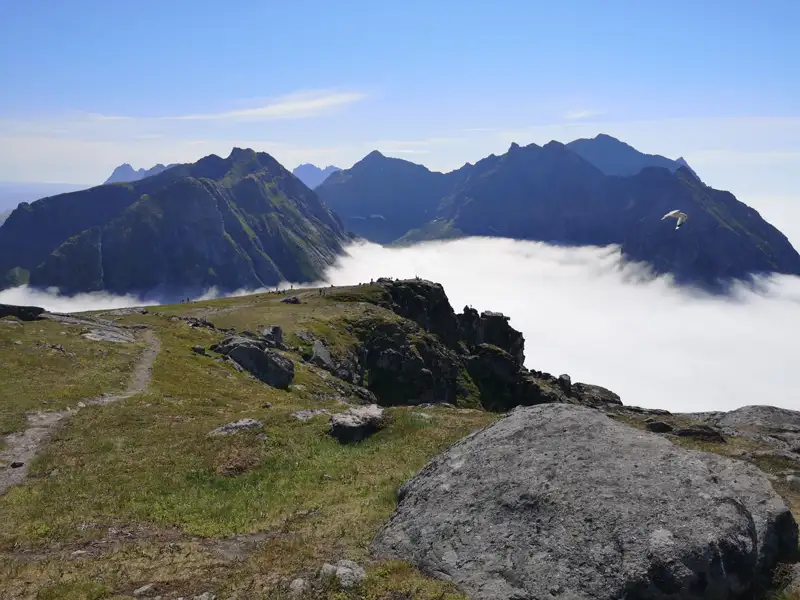 Blick von einem Bergplateau auf ein Wolkenmeer und umliegende Bergketten.