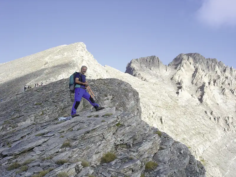 Wanderer auf einem Bergpfad mit Blick auf einen Berggipfel.