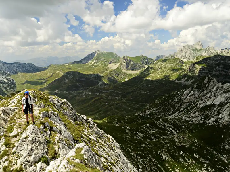 Wanderer auf einem Berggrat inmitten einer Berglandschaft.