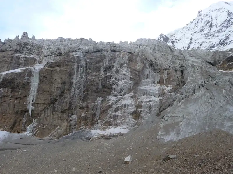 Eisformationen und schneebedeckte Felswand im Hochgebirge.