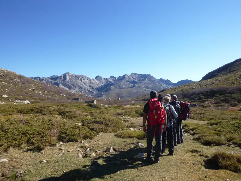 Wanderer mit Rucksäcken auf einem Bergpfad.