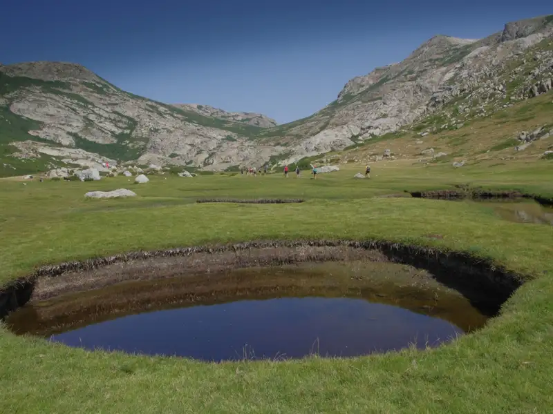 Wanderer in einer Berglandschaft mit kleinem See.