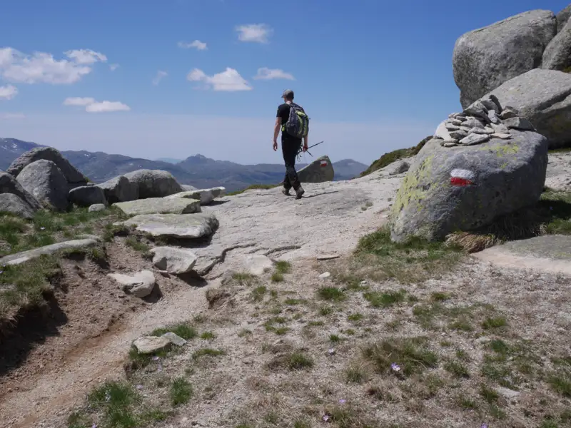 Wanderer auf einem Bergpfad mit rot-weißer Wegmarkierung.