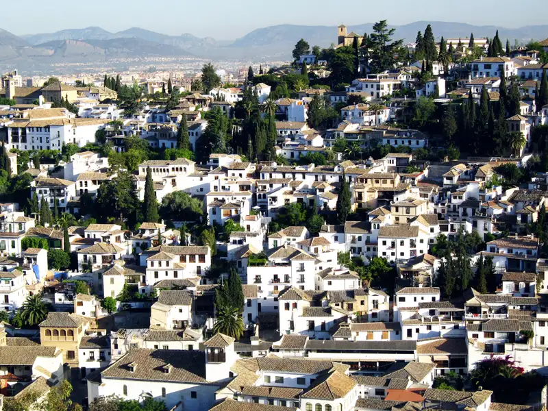 Blick über die Dächer des Albaicín-Viertels mit seinen weiß getünchten Häusern und grünen Bäumen in Granada, Spanien.