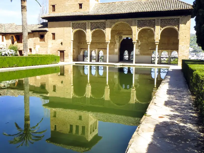 Reflektion eines Gebäudes mit Bögen in einem Wasserbecken.