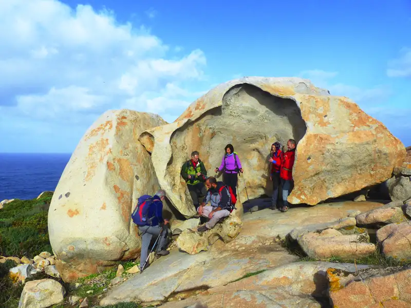 Wanderer ruhen sich an einem großen, ausgehöhlten Felsen während ihrer Wanderung aus.