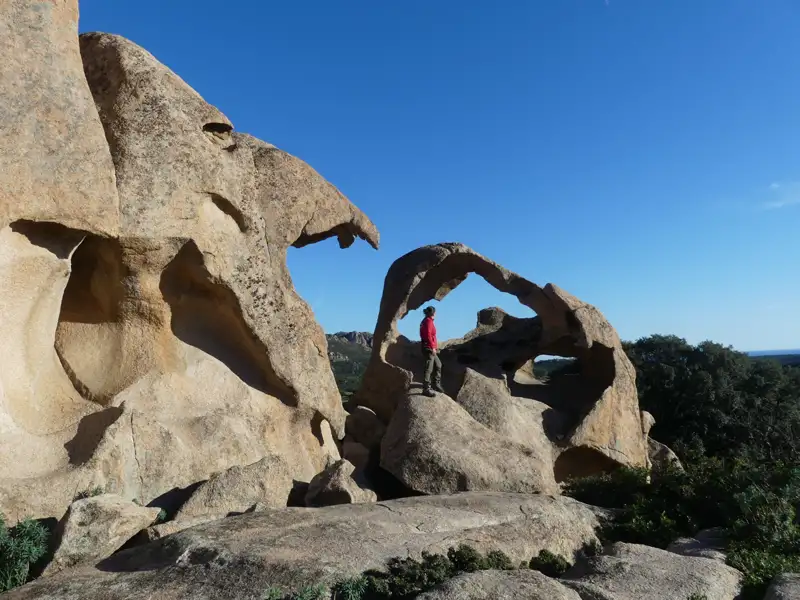 Wanderer auf einem Felsbogen inmitten einer bizarren Felsformation.