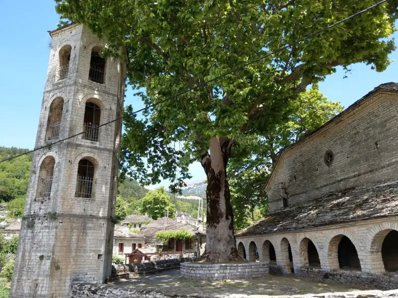 Historischer Glockenturm und Kirche in einem Dorf.