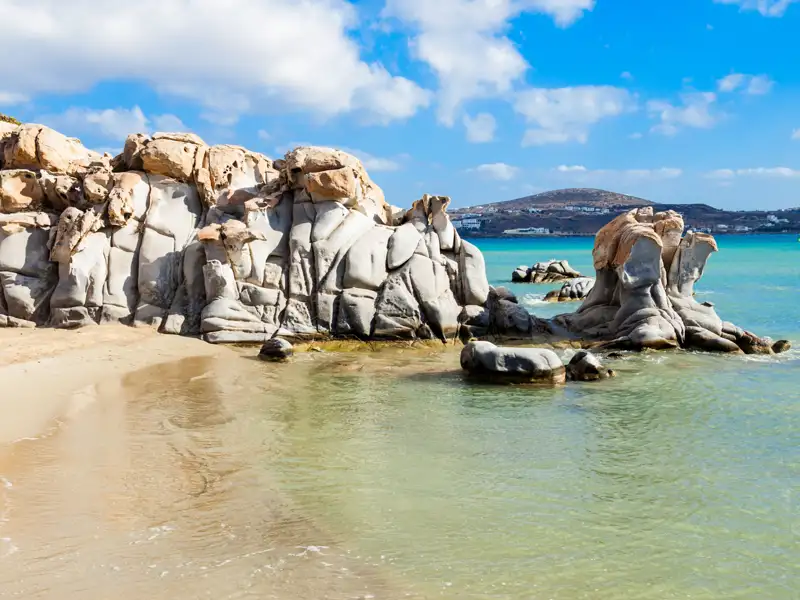 Bizarre Felsformationen an einem Strand mit türkisfarbenem Wasser.