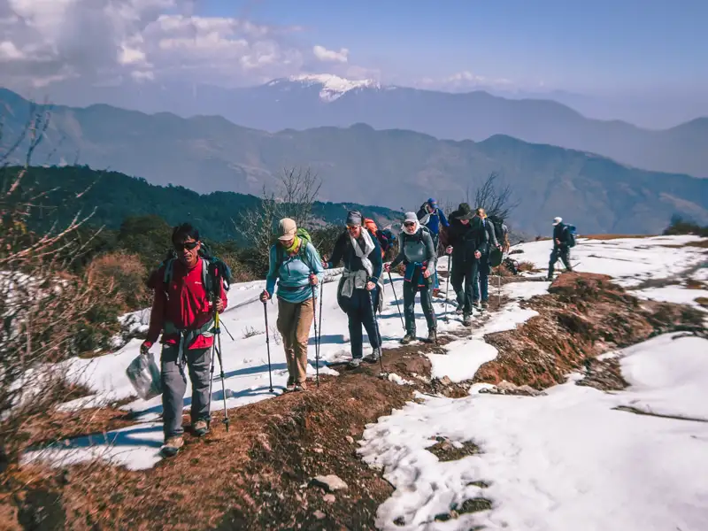 Wandergruppe auf einem verschneiten Bergpfad in den Bergen.