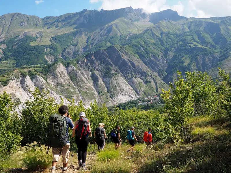 Wanderer auf einem Bergpfad mit Blick auf das Tal und die Berge.