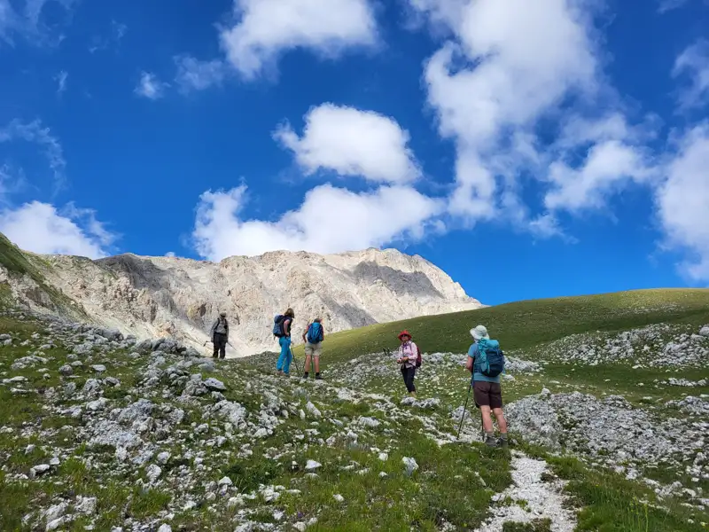 Wanderer auf einem Bergpfad mit Blick auf einen Berggipfel.