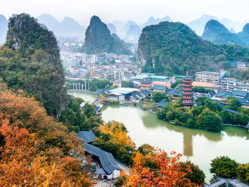 Panorama einer Stadtlandschaft mit Karstbergen und einer Pagode am See.