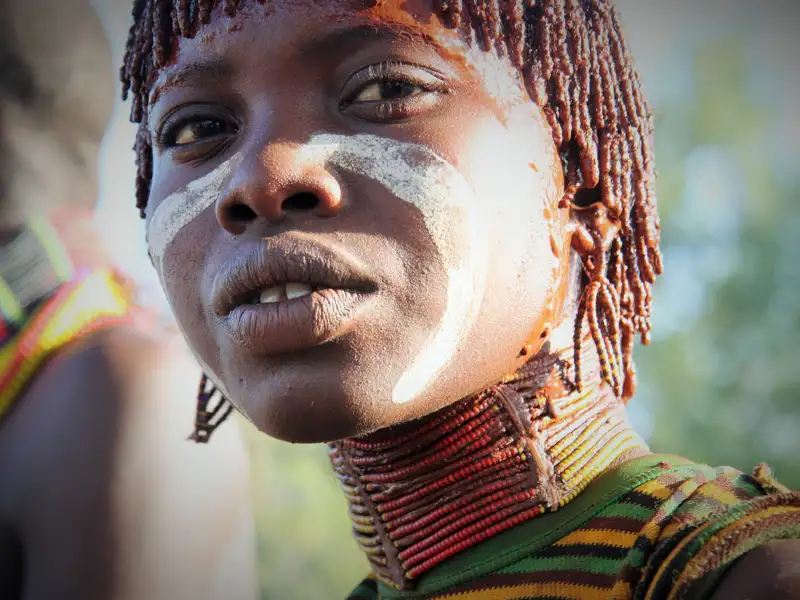 Person mit traditioneller Gesichtsbemalung und Halskette.