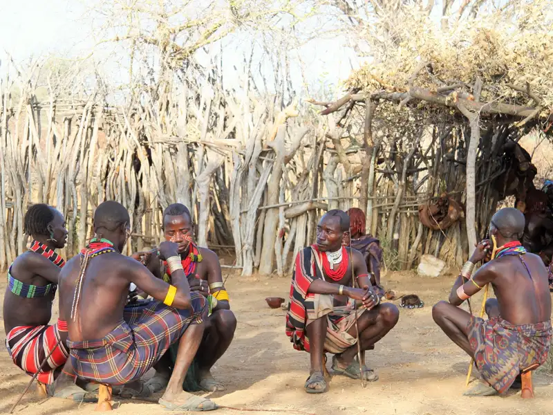 Mitglieder eines einheimischen Stammes treffen sich vor ihrer traditionellen Behausung.