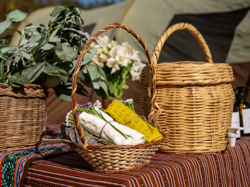 Körbe mit Reiseutensilien wie Handtüchern und Pflanzen vor einem Zelt.