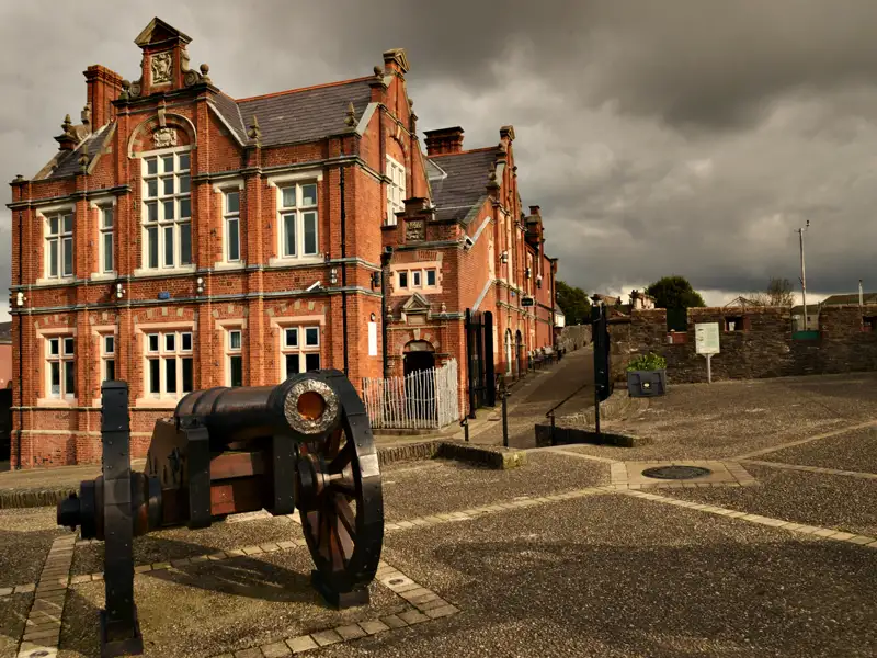 Historische Kanone vor einem Backsteingebäude.
