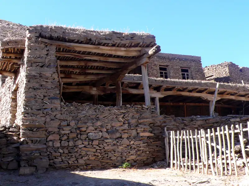 Traditionelles Steinhaus mit Holzbalken und einem Holzzaun.