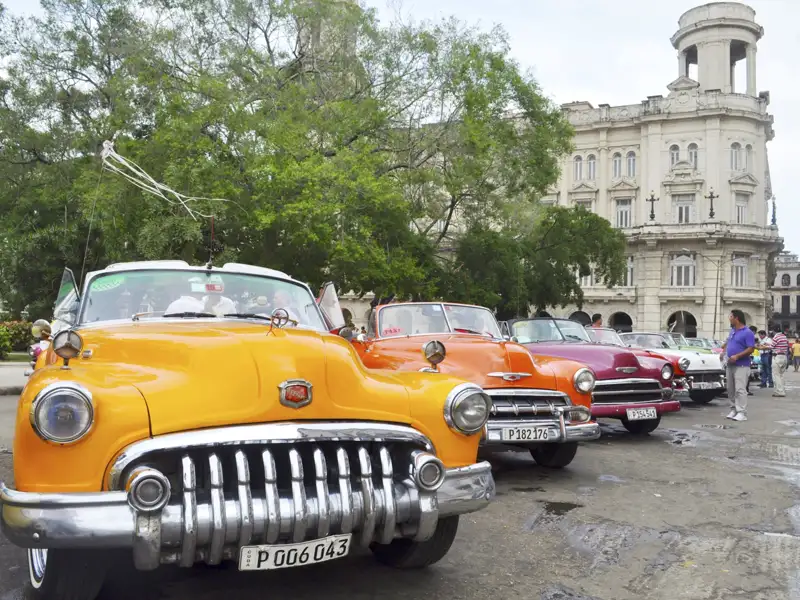 Straßenszene in Kuba mit bunten Häusern und einer Kirche.