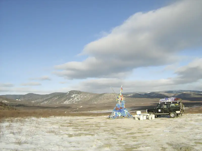 Geländewagen und geschmücktes Objekt in winterlicher Landschaft.