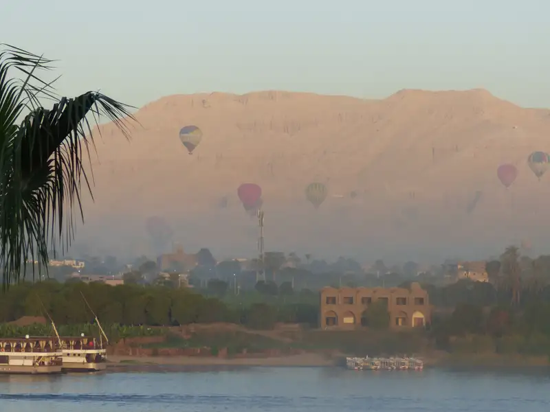Heißluftballons steigen über den Nil auf, mit Blick auf die Berge und den Fluss.