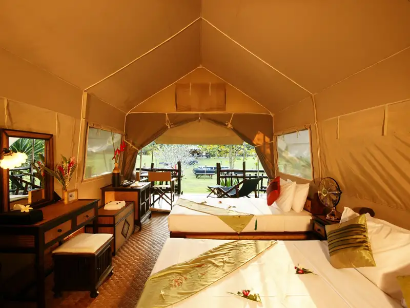 Innenansicht eines Safari-Zeltes mit komfortablen Betten und Möbeln.