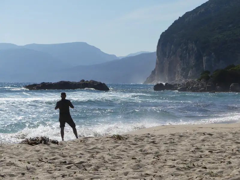 Person am Strand mit Blick auf das Meer und die Klippen.