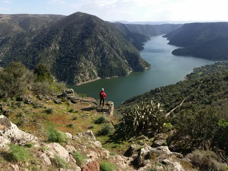 Wanderer auf einem Aussichtspunkt mit Blick auf den Fluss und die Berge.