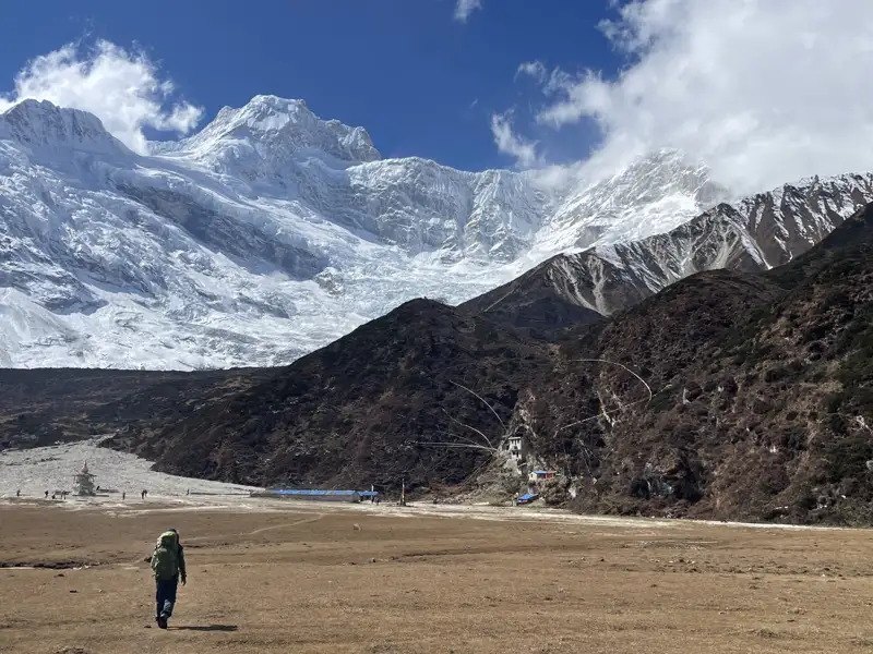 Wanderer in einer hochgelegenen Landschaft mit Blick auf schneebedeckte Berge und Gletscher.