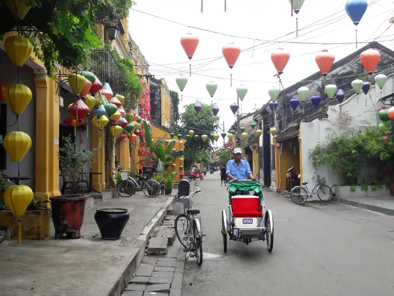 Traditionelle Straße mit bunten Laternen und einem Rikschafahrer.