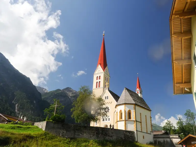 Kirche mit roten Türmen in einem Bergdorf.