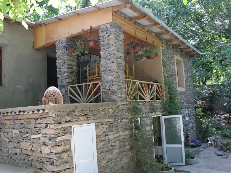 Steinhaus mit Balkon und bepflanzten Blumenkübeln.